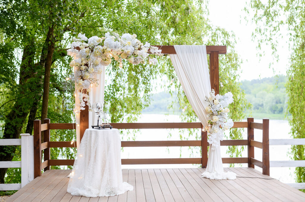 Une arche de mariage rectangulaire avec du voilage et une composition fleurie