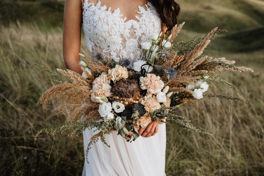 Une mariée avec un bouquet de style hippie bohème avec des fleurs séchées